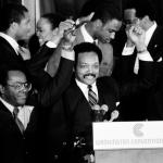 FILE - Jesse Jackson holds his hands up after announcing he will seek the Democratic nomination for president, with his campaign chairman Mayor Richard Hatcher, left, of Gary Ind., and Mayor Marion Barry of Washington, D.C., in Washington, Nov. 3, 1983. (AP Photo/Scott Stewart, File)