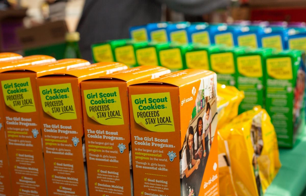 : A closeup view of several varieties of Girl Scout Cookies on display on a table.