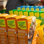 : A closeup view of several varieties of Girl Scout Cookies on display on a table.