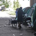 A volunteer with Street Samaritans hands out a care package to a person camping underneath a bridge in November in the Chicago area. (Medill Illinois News Bureau by Jacques Abou-Rizk)