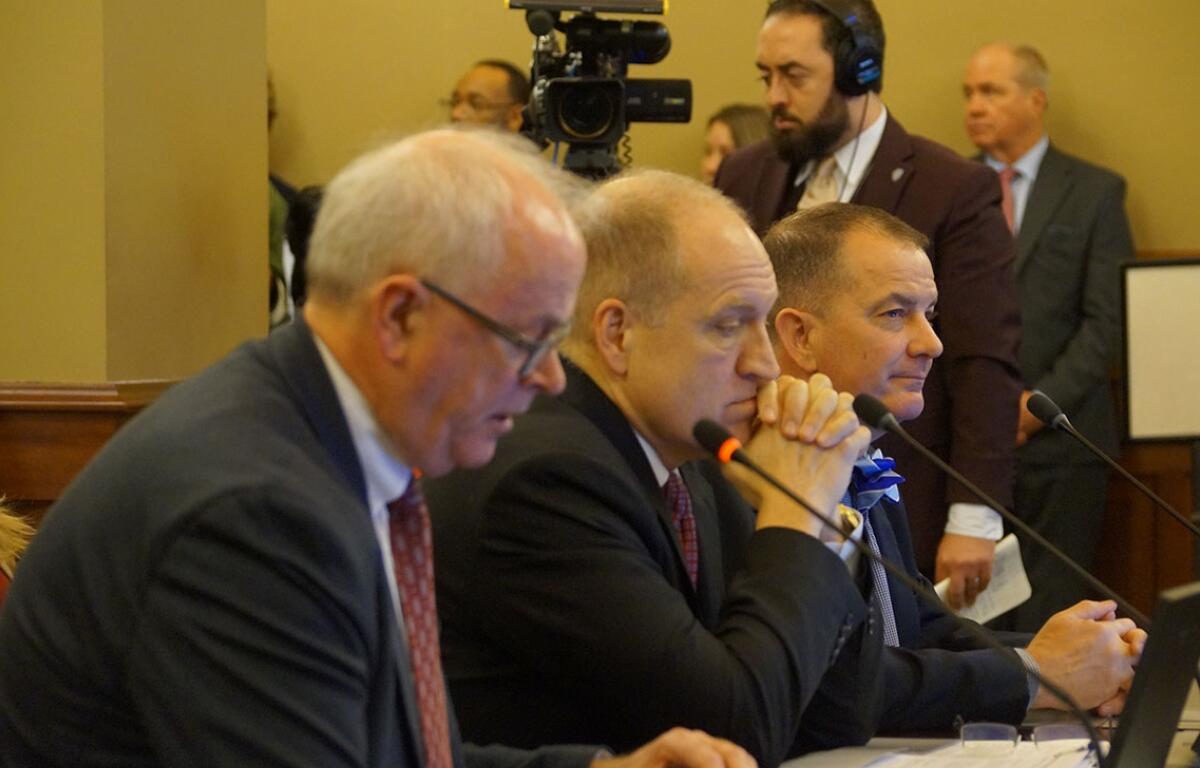 Nicholas Jones, left, executive vice president of the University of Illinois System, testifies before a House Committee opposing a bill to overhaul the way Illinois funds public universities. Also testifying in favor of the bill are Southern Illinois University System President Daniel Mahoney, center, and Eastern Illinois University President Jay Gatrell. (Capitol News Illinois photo by Peter Hancock)