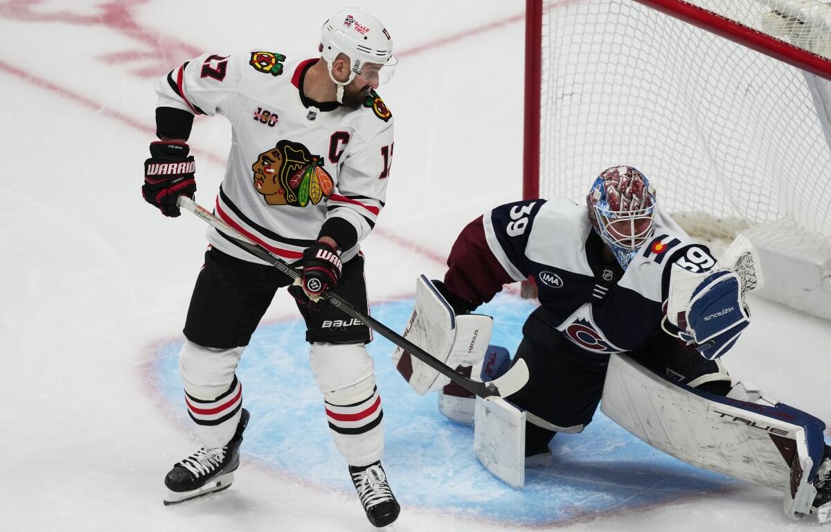 Chicago Blackhawks left wing Nick Foligno, left, redircts a shot into the glove of Colorado Avalanche goaltender MacKenzie Blackwood in the third period of an NHL hockey game Saturday, Feb. 28, 2026, in Denver. (AP Photo/David Zalubowski)