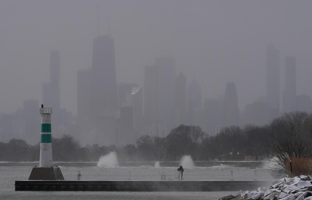 A person bundles up and fishes on a breakwater by Montrose Harbor, Monday morning, March 16, 2026, in downtown Chicago. (AP Photo/Kiichiro Sato)