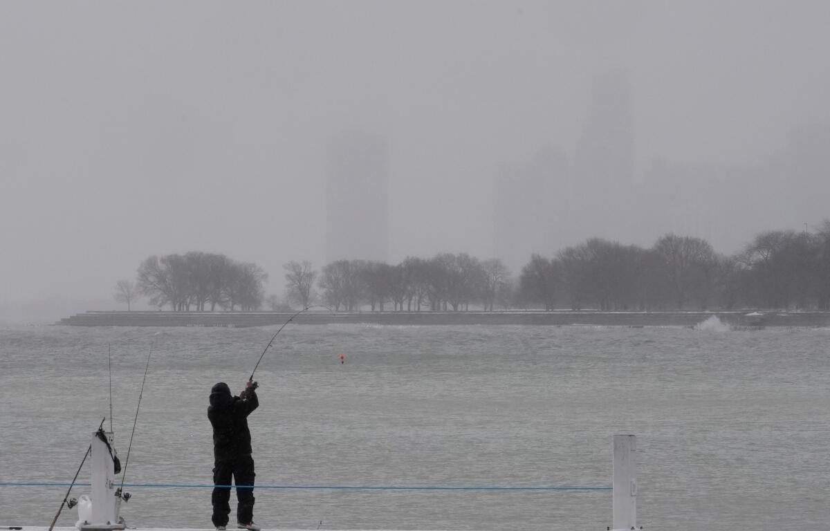 A person bundles up and fishes on a breakwater by Montrose Harbor, Monday morning, March 16, 2026, in downtown Chicago. (AP Photo/Kiichiro Sato)