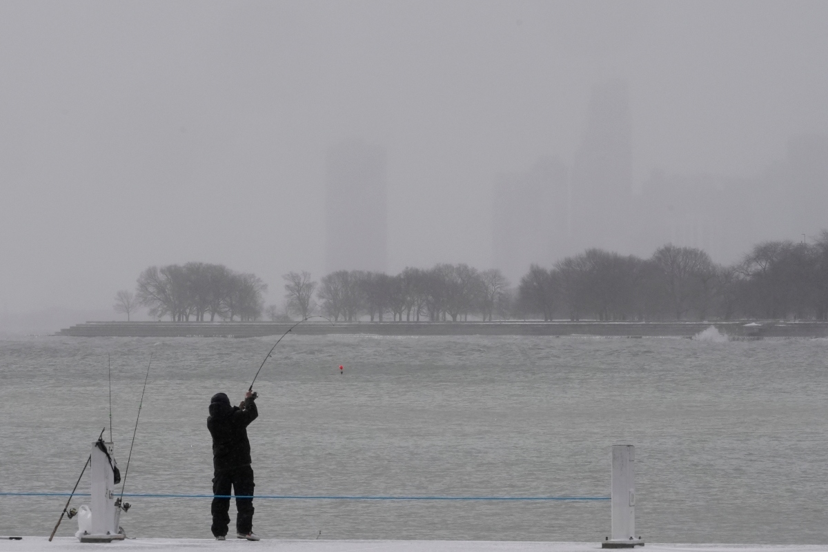 A person bundles up and fishes on a breakwater by Montrose Harbor, Monday morning, March 16, 2026, in downtown Chicago. (AP Photo/Kiichiro Sato)