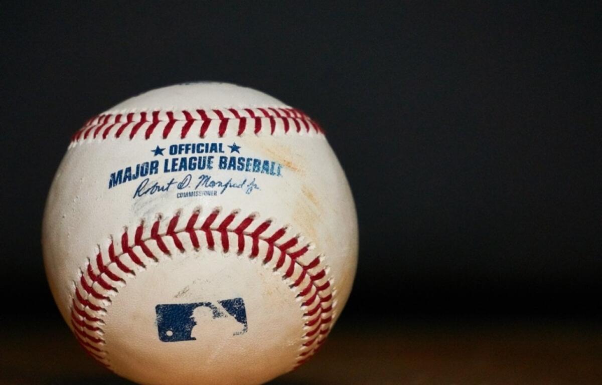 Official Major League Baseball with blue logo and red seams on a dark background.