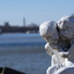 A statue of two angels showing the consequences of air pollution is seen with their backs to the Illinois river and the Powerton coal plant. (Medill Illinois News Bureau photo by Gabriel Castilho)