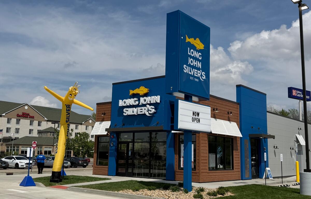 Long John Silver's storefront with a tall yellow inflatable fish outside and a 'Now Open' marquee in front.