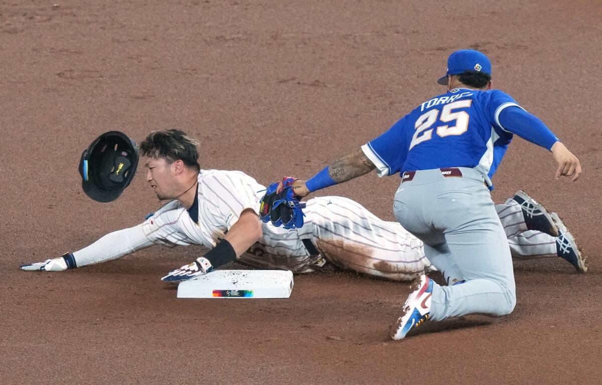 Japan's Seiya Suzuki is tagged out at second base by Venezuela's Gleyber Torres during the first inning of a World Baseball Classic quarterfinal game against Japan, Saturday, March 14, 2026, in Miami. (AP Photo/Marta Lavandier)