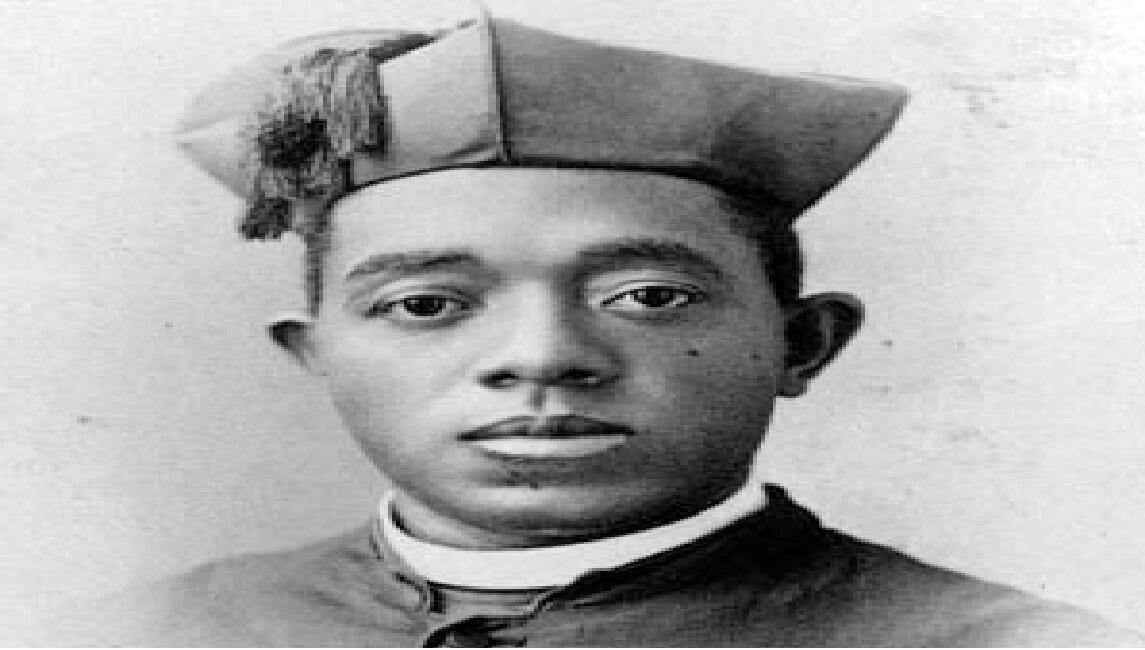 Young man in a graduation cap and gown facing the camera (black-and-white portrait).