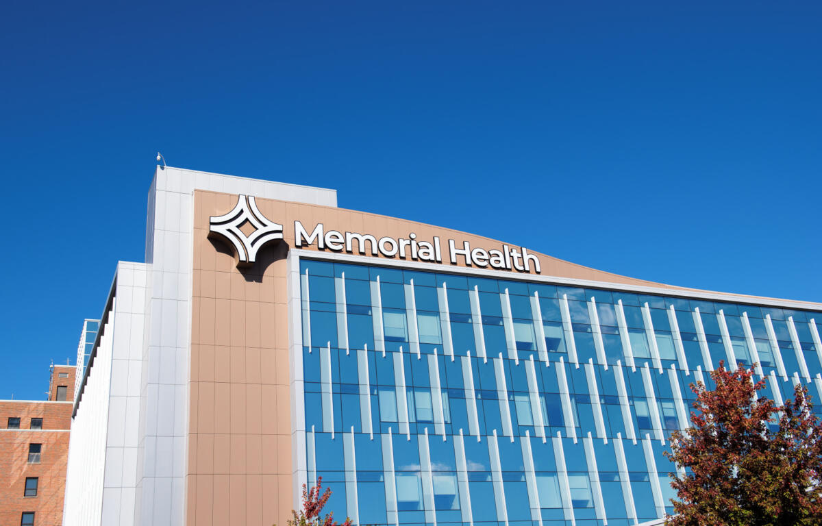 Memorial Health building exterior with glass windows against a clear blue sky and a distinctive logo sign.