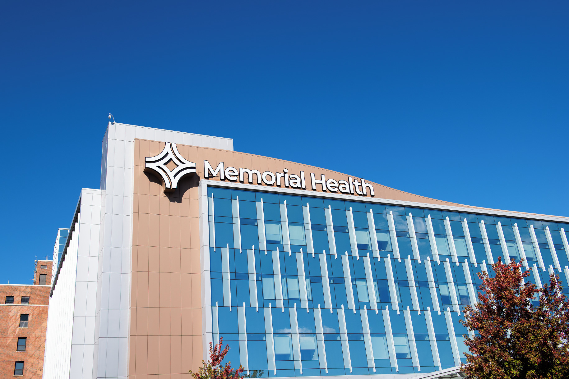 Memorial Health building exterior with glass windows against a clear blue sky and a distinctive logo sign.
