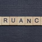 Wooden letter tiles spell the word 'TRUANCY' on a dark textured background.