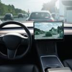 Interior of a modern car showing a steering wheel and a large central touchscreen displaying a highway with other vehicles ahead.