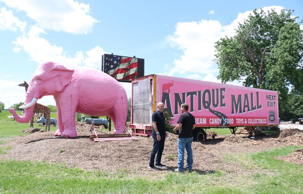 Felipe de la Cruz Tenorio and Wayne Pickerill stood in front of the iconic pink elephant statue and vintage trailer at the Pink Elephant Antique Mall. (Medill Illinois News Bureau photo by Chloe Park)