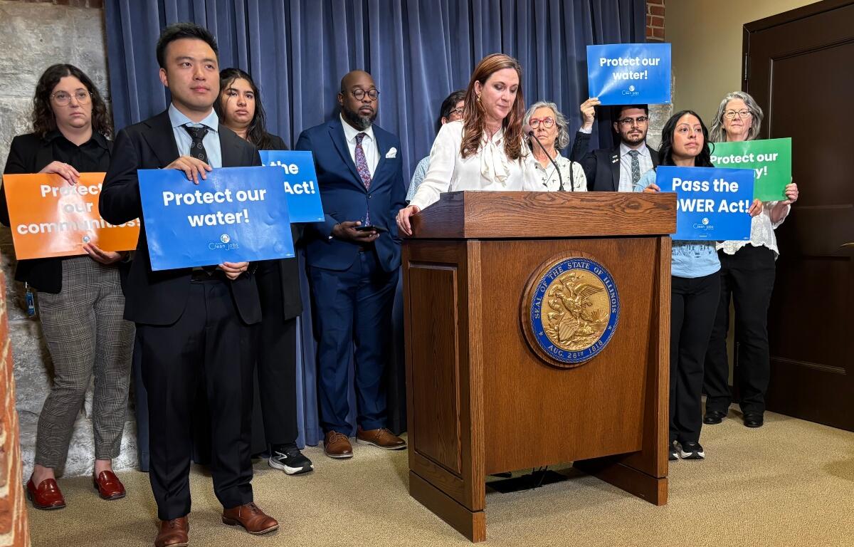 Diverse group at a press conference behind a podium, holding signs that urge Protect our water and Pass the POWER Act.