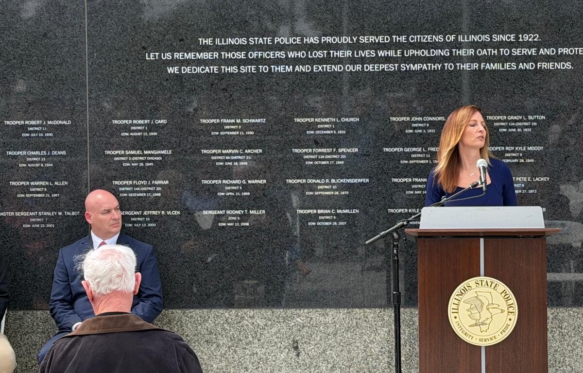 Michelle Hanneken, right, speaks at a memorial service held at the Illinois State Police Memorial Wall Wednesday, May 6, while Illinois State Police Heritage Foundation Executive Director Jarod Ingebrigtsen listens.