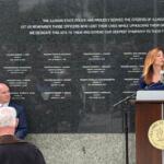Michelle Hanneken, right, speaks at a memorial service held at the Illinois State Police Memorial Wall Wednesday, May 6, while Illinois State Police Heritage Foundation Executive Director Jarod Ingebrigtsen listens.