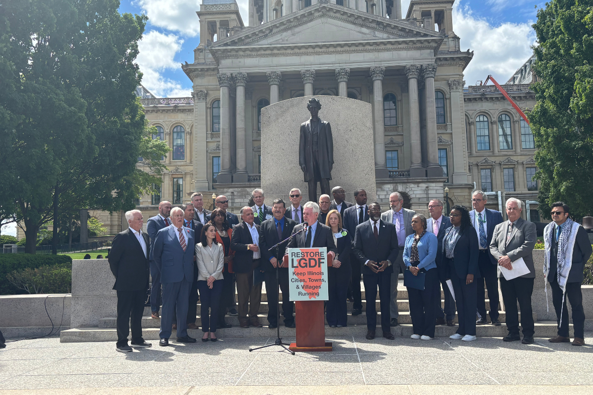 Group of officials and supporters on the steps in front of a statue at a government building, giving a press conference for Restore LGDF.