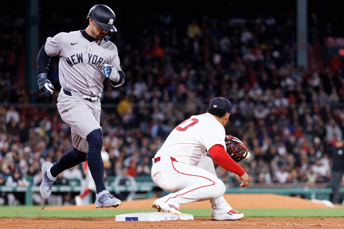 Yankees baserunner in gray uniform races toward second base as a Red Sox fielder guards the bag; crowded ballpark in background.