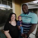 Farra White poses with her 1-year-old daughter, Olivia, and husband Marlon White outside their residence Thursday, May 7, 2026, in Fort Collins, Colo. (AP Photo/David Zalubowski)