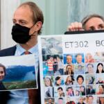 Man in a suit and black mask holds a landscape photo next to a large poster labeled ET302 Boeing with many portrait thumbnails.