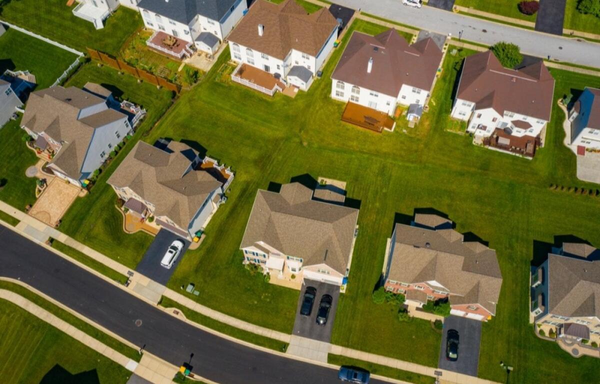 Aerial view of a suburban residential neighborhood with well-kept lawns, two-story houses, and a curved street.