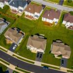 Aerial view of a suburban residential neighborhood with well-kept lawns, two-story houses, and a curved street.