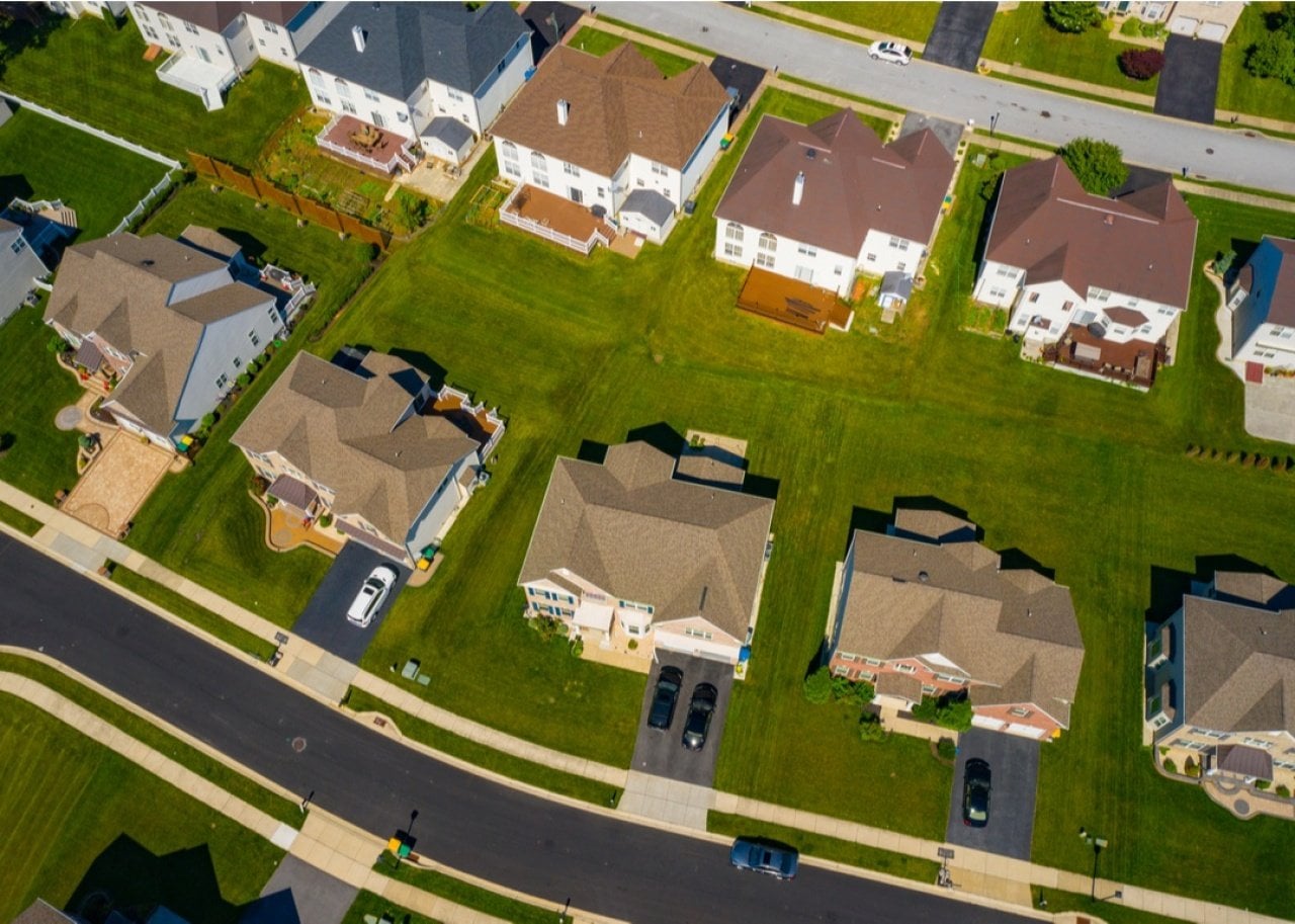 Aerial view of a suburban residential neighborhood with well-kept lawns, two-story houses, and a curved street.