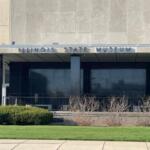 Illinois State Museum building facade with glass entrance and manicured lawn in front