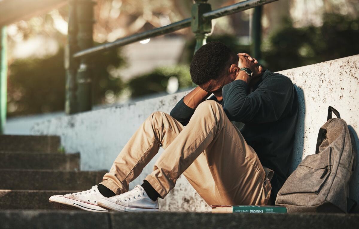 Student, mental health and depression with anxiety, burnout and sad for exam results, fail or mistake while sitting outdoor. Young man, stress and tired and depressed on university or college campus