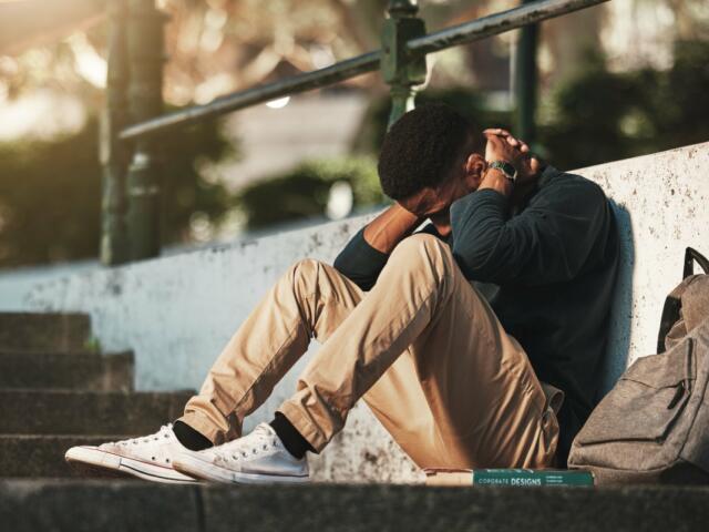 Student, mental health and depression with anxiety, burnout and sad for exam results, fail or mistake while sitting outdoor. Young man, stress and tired and depressed on university or college campus