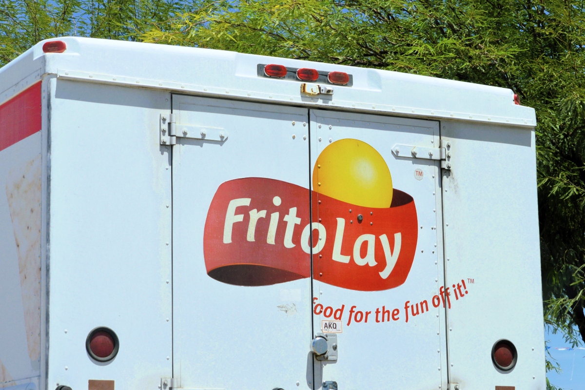 Rear of a light blue Frito-Lay delivery truck with the yellow sun logo and the slogan 'Food for the fun of it!'
