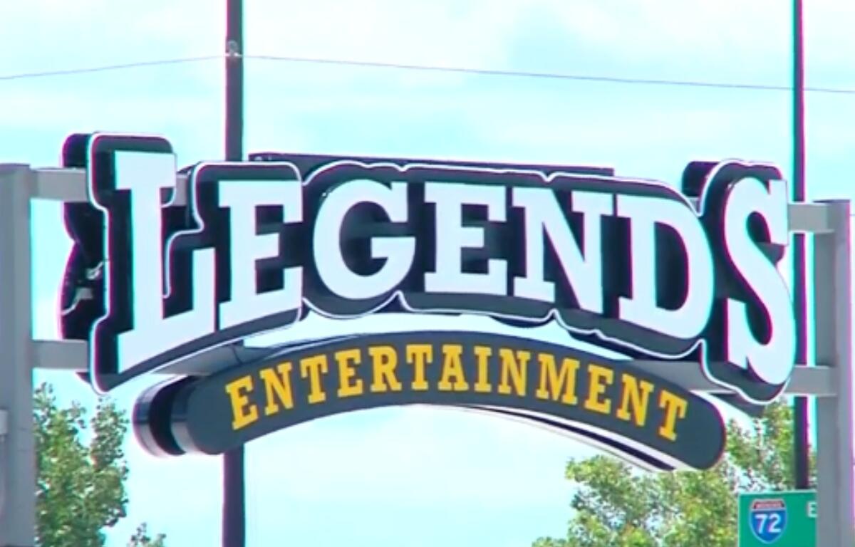 Legends Entertainment sign with large white letters and a curved yellow 'ENTERTAINMENT' banner beneath it against a blue sky.