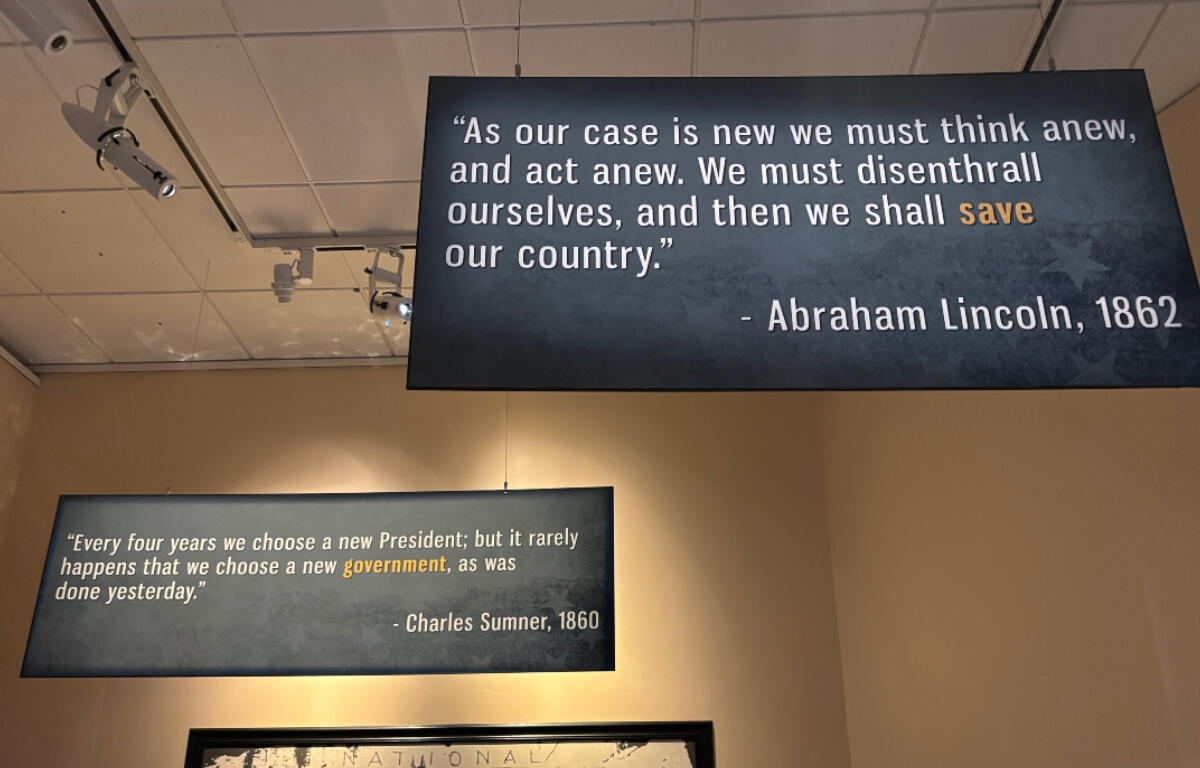 Two hanging blue quote boards on a museum wall; Lincoln (1862) quote about thinking anew and saving the country, and Sumner (1860) quote about government.