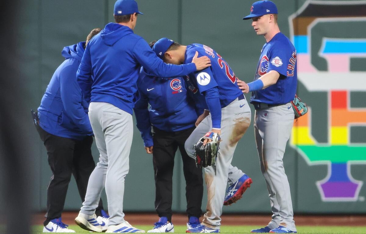 Chicago Cubs right fielder Seiya Suzuki, center front, is checked after being injured while attempting to catch a fly ball during the fourth inning of a baseball game against the San Francisco Giants, Saturday, June 13, 2026, in San Francisco, Calif. (AP Photo/Scott Marshall)