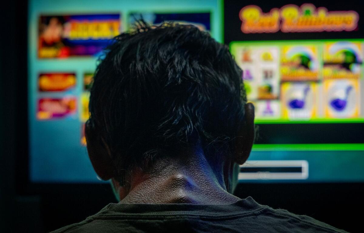 A man spends the last three dollars in his pocket playing a bar slot machine in downstate Golconda on June 4, and then leaves. (Credit: Julia Rendleman for Capitol News Illinois)