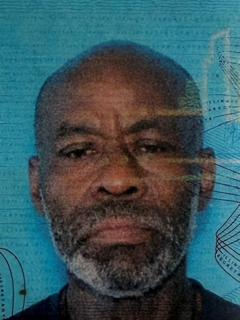 Close-up portrait of a middle-aged man with a gray beard, looking straight ahead, against a blue textured background.