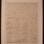 Framed parchment with dense handwritten text displayed on a wall/gallery setting.