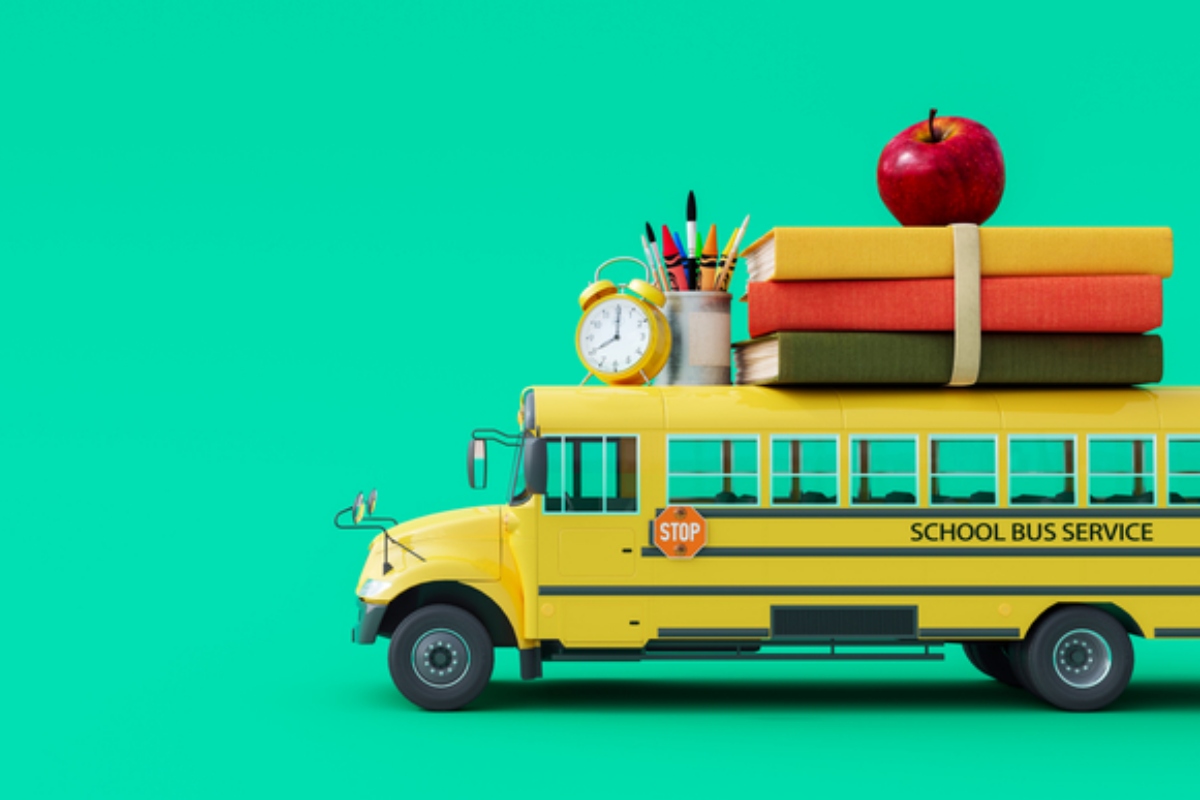 Back-to-school scene: yellow school bus with books, an apple, clock, and pencils on top against a teal background.
