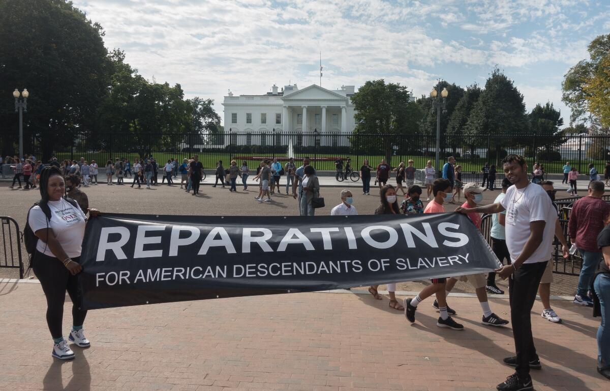 WASHINGTON, DC - OCT. 16, 2021: White House in bg, activists rally to demand Pres. Biden sign an executive order to study reparations, and establish a commission for descendants of American slavery.
