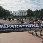 WASHINGTON, DC - OCT. 16, 2021: White House in bg, activists rally to demand Pres. Biden sign an executive order to study reparations, and establish a commission for descendants of American slavery.