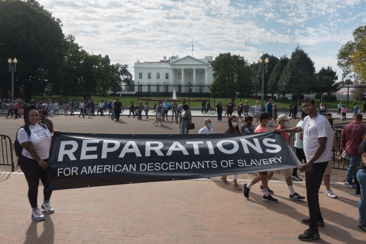 WASHINGTON, DC - OCT. 16, 2021: White House in bg, activists rally to demand Pres. Biden sign an executive order to study reparations, and establish a commission for descendants of American slavery.