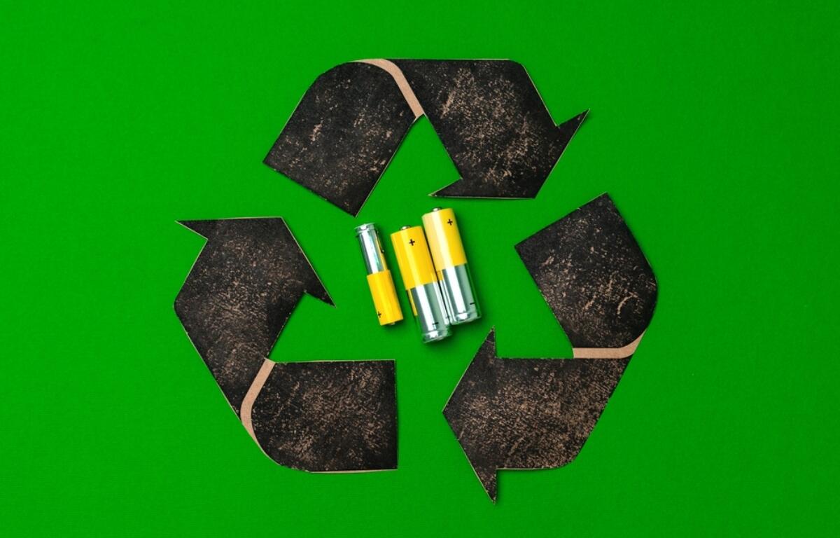 Recycling symbol formed by four black arrow shapes on a bright green background, with three batteries in the center.