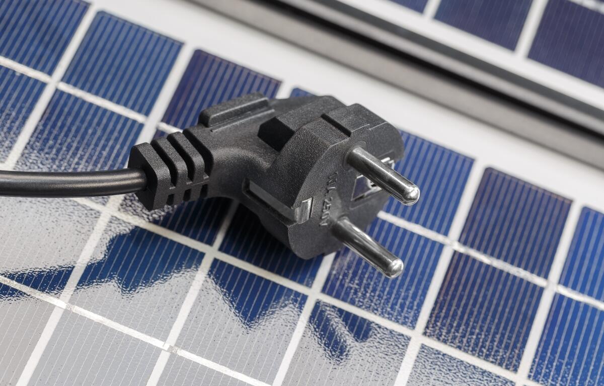 An electric plug lies on the solar panels. The concept of environmentally friendly solar energy.
