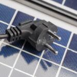 An electric plug lies on the solar panels. The concept of environmentally friendly solar energy.