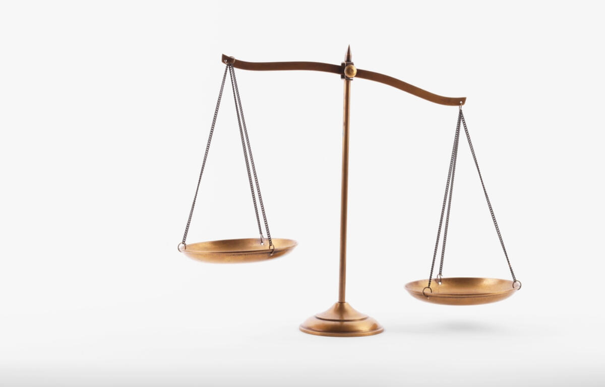 Brass balance scale with two hanging pans, symbolizing justice and fairness on a white background.