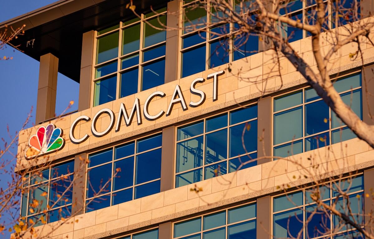 Exterior view of a modern office building with a prominent 'COMCAST' sign and NBC peacock logo on the facade