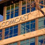 Exterior view of a modern office building with a prominent 'COMCAST' sign and NBC peacock logo on the facade