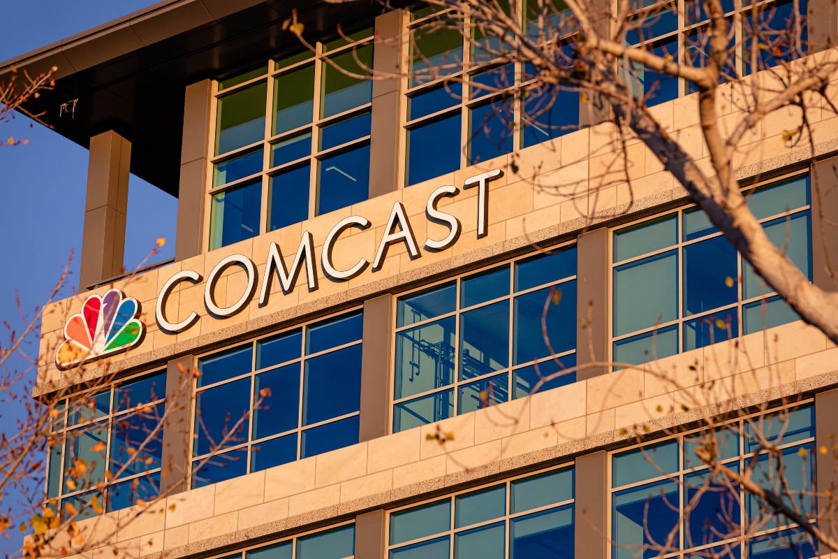 Exterior view of a modern office building with a prominent 'COMCAST' sign and NBC peacock logo on the facade